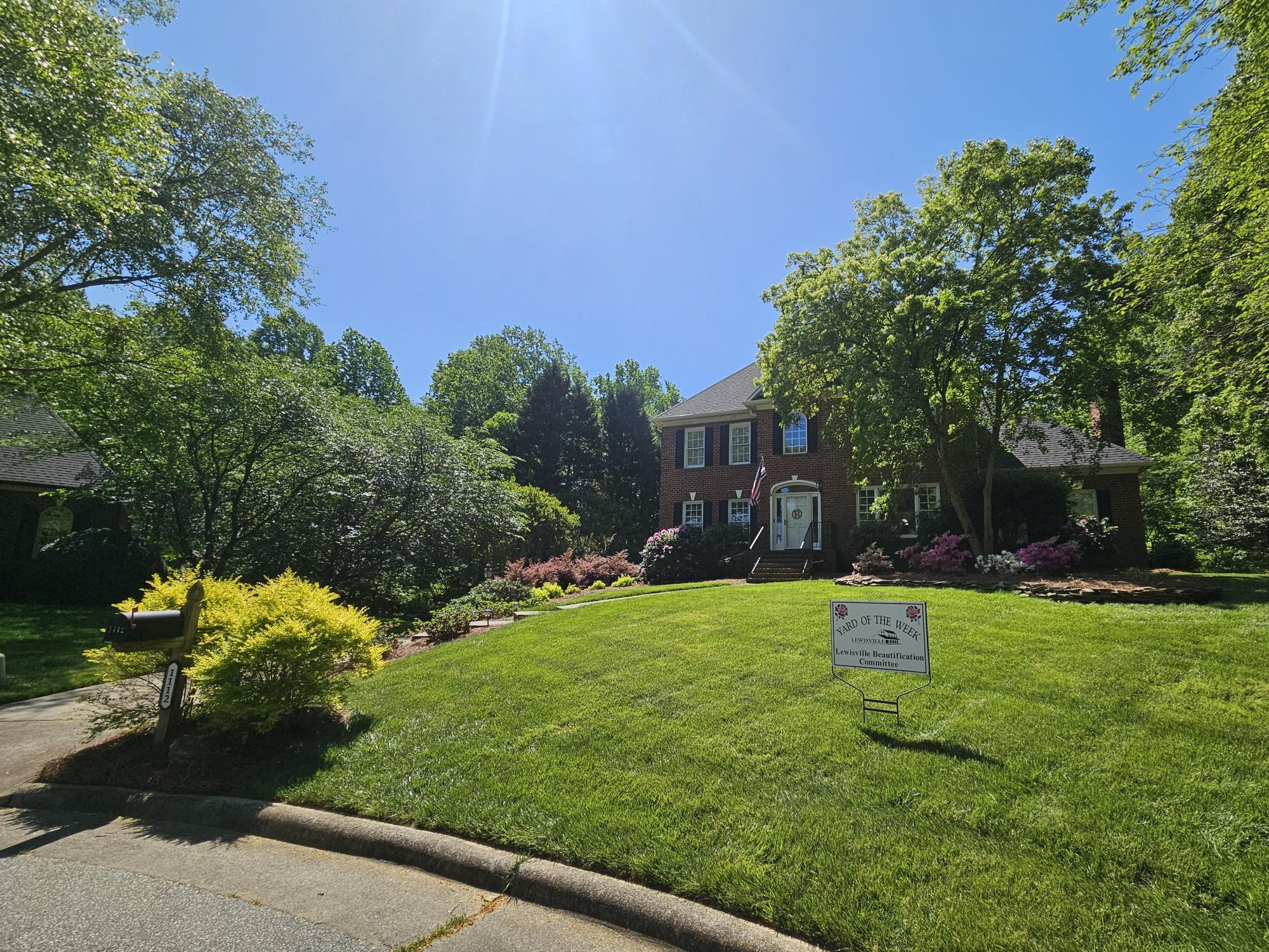 A manicured lawn in front of a brick house