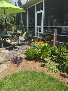 Beautiful landscaping surrounds a summer themed porch