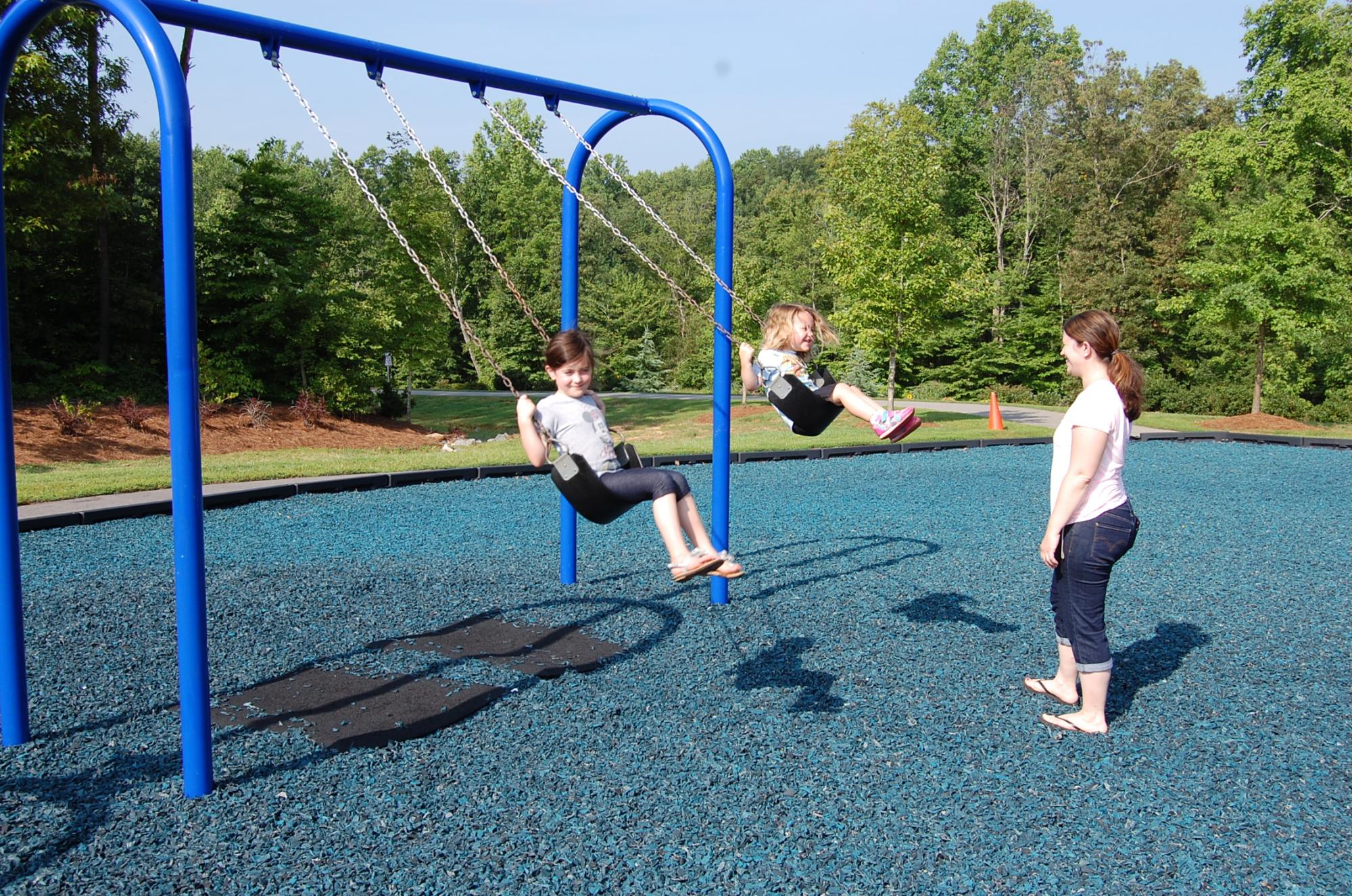 Family enjoying the swing set at the playground at Jack Warren Park