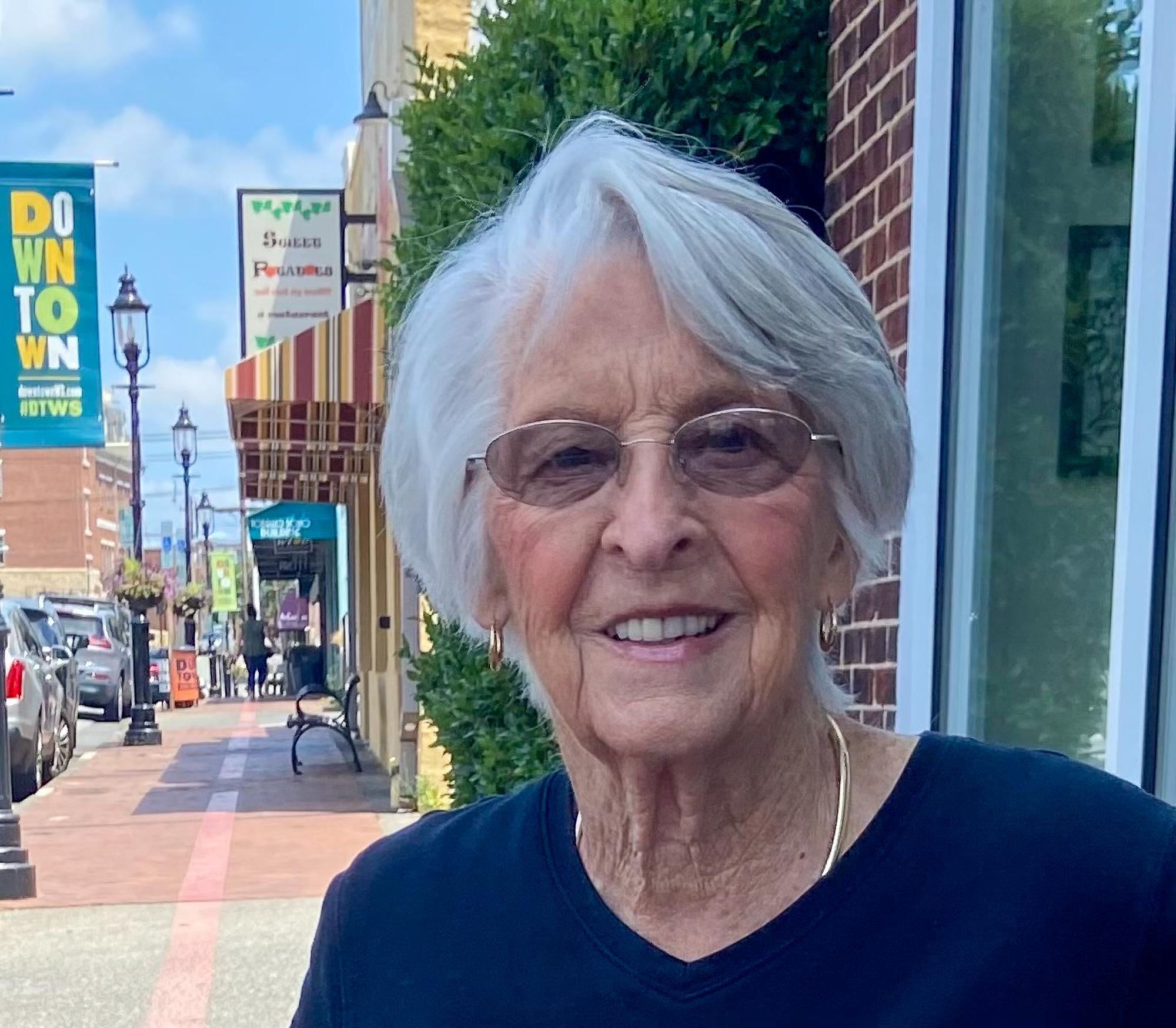 Woman with gray hair smiling in a busy downtown setting