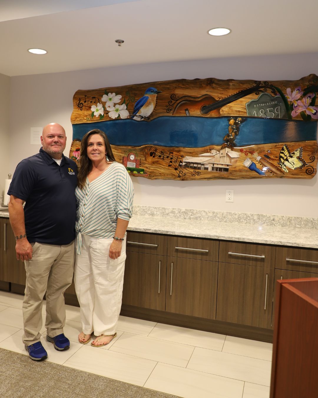 Missy and Jason stand next to the Beginnings mural at the Mary Alice Warren Community Center in Lewisville, North Carolina.